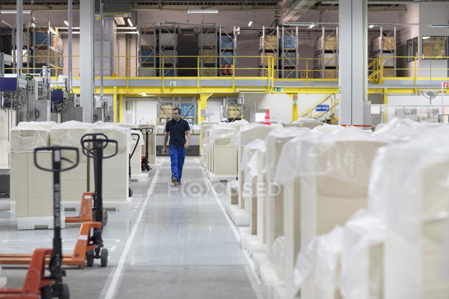 Trabajador caminando a través de fábrica de embalaje de papel - foto de stock