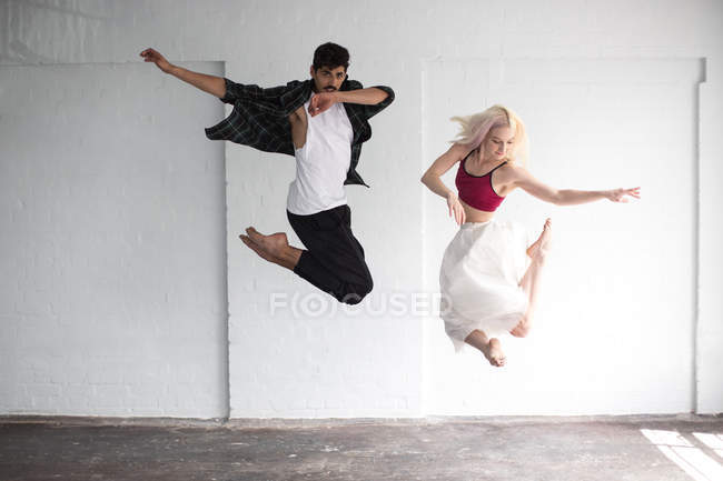 Bailarines practicando saltos en estudio vacío - foto de stock