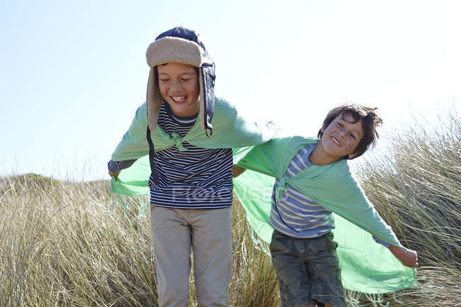 Two young boys, wearing fancy dress, playing on beach — Stock Photo