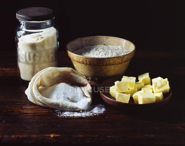 Harina, azúcar y mantequilla en la superficie de madera - foto de stock