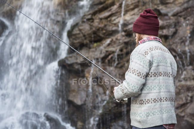 Man fishing by waterfall — Stock Photo
