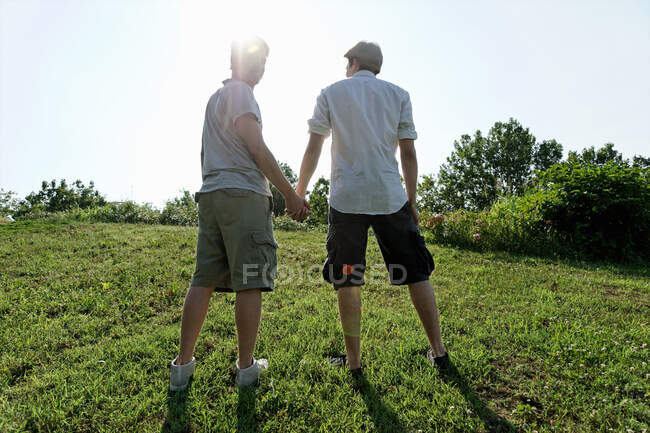Dos jóvenes caminando y tomados de la mano - foto de stock