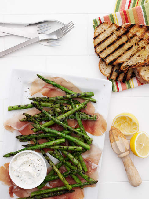 Plates of ham, asparagus, and bread — Stock Photo