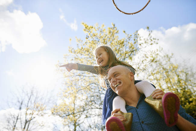 Father carrying daughter on shoulders at park — Stock Photo