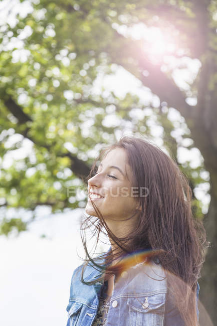 Adolescente disfrutando de la brisa al aire libre en retroiluminación - foto de stock
