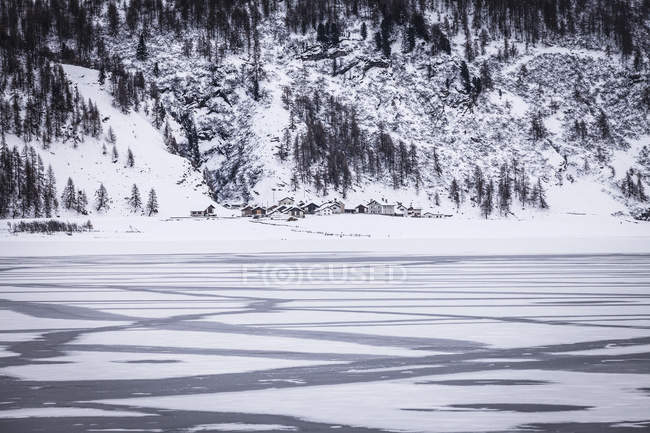 Lago e aldeia congelados sob a montanha coberta de neve, Engadin, Suíça — Fotografia de Stock