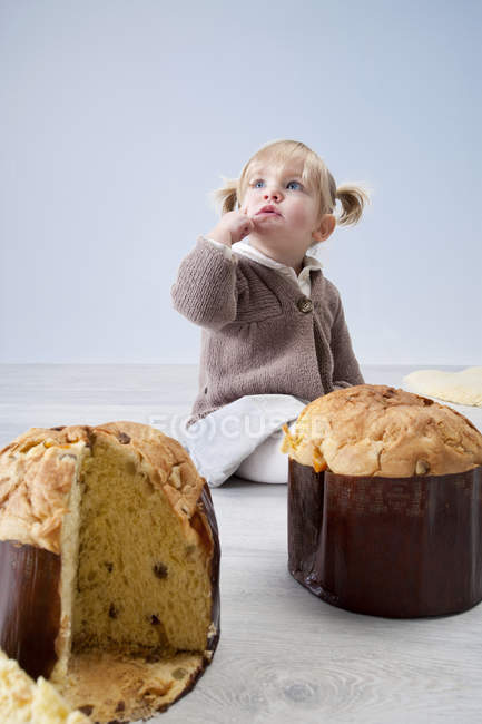 Femmina bambino seduto sul pavimento con torte pannetone — Foto stock