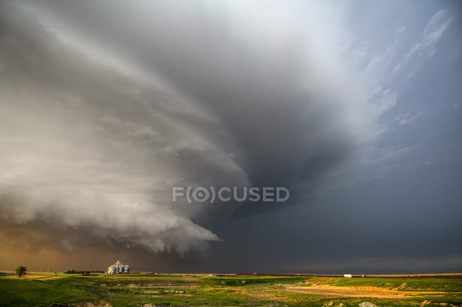 Tormenta eléctrica de supercélulas productoras de tornados girando sobre tierras de rancho al atardecer cerca de Leoti, Kansas - foto de stock