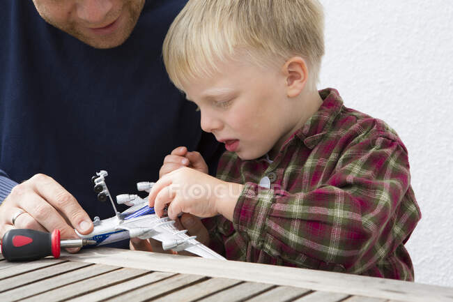 Homem adulto médio e filho preparando avião de brinquedo na mesa do pátio — Fotografia de Stock
