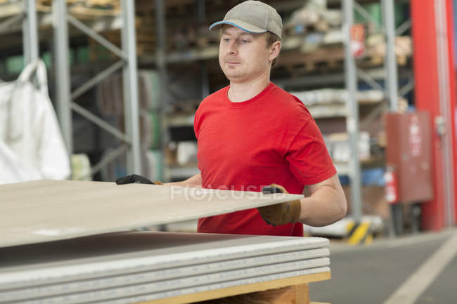 Worker lifting boards in hardware store warehouse — Stock Photo
