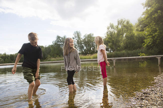Hermano y dos hermanas remando en el agua del lago - foto de stock
