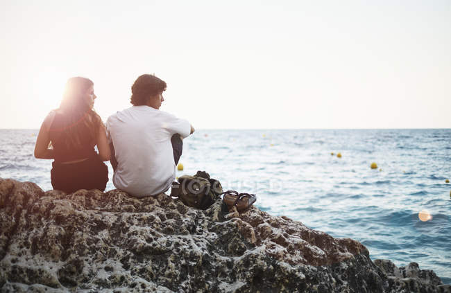 Visão traseira do jovem e da irmã adolescente na praia rochosa, Javea, Espanha — Fotografia de Stock