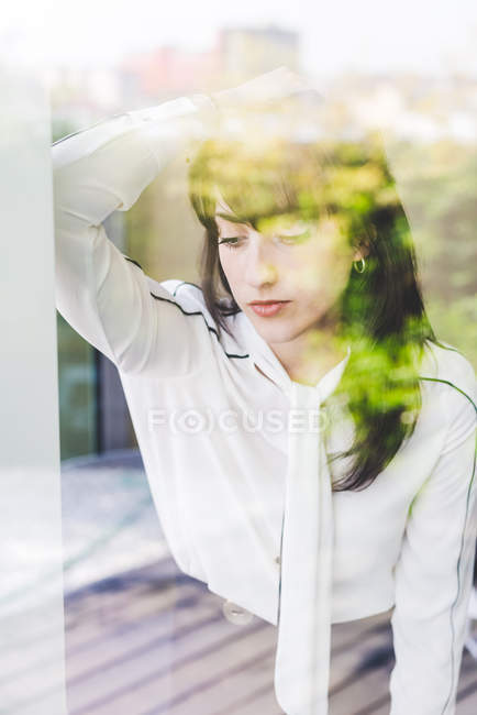 Window view of businesswoman daydreaming in office — Stock Photo