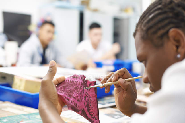 Pintura estudantil masculina na amostra de tecido na classe têxtil — Fotografia de Stock