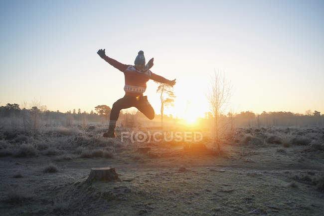 Hombre saltando en invierno la luz del sol - foto de stock