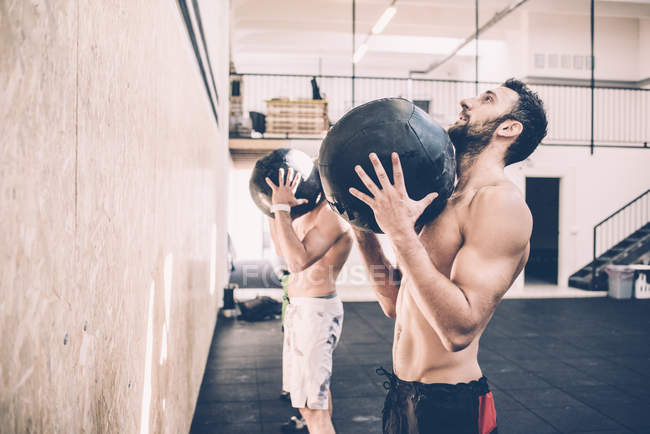 Deux entraîneurs masculins tenant des balles d'exercice dans la salle de gym — Photo de stock