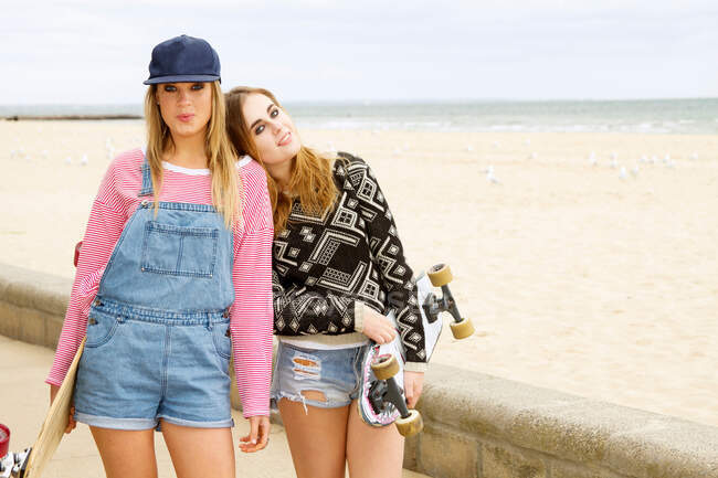 Two young women holding skateboards at beach — Stock Photo