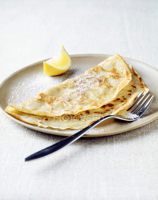 Pancake with lemon wedge and sugar on plate — Stock Photo