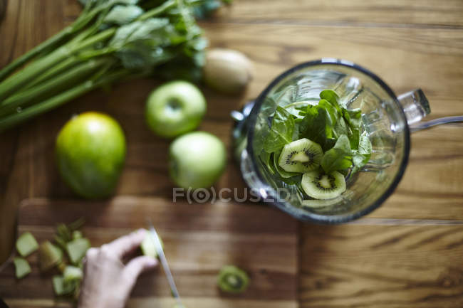 Mulher corte quivi verde na mesa de madeira — Fotografia de Stock