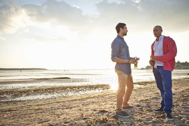 Homens bebendo cerveja e conversando na praia — Fotografia de Stock