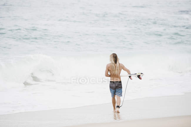 Australian surfer with surfboard on beach — Stock Photo