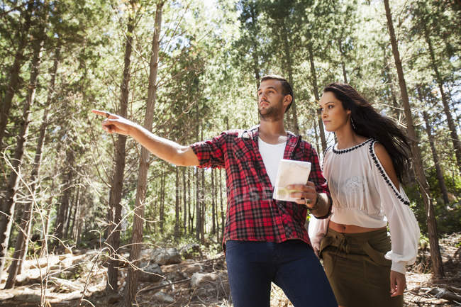 Young couple in forest, man pointing — Stock Photo