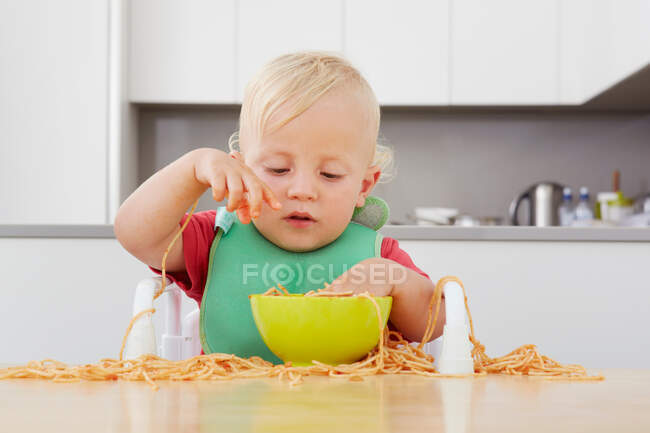 Тоддлер играет со спагетти — стоковое фото