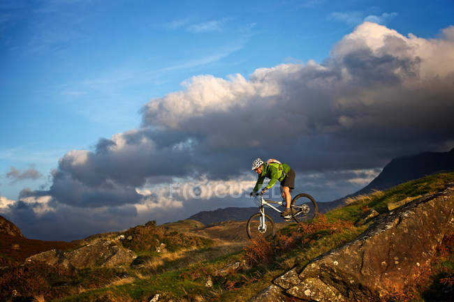 Mountain biker on grassy hillside — Stock Photo