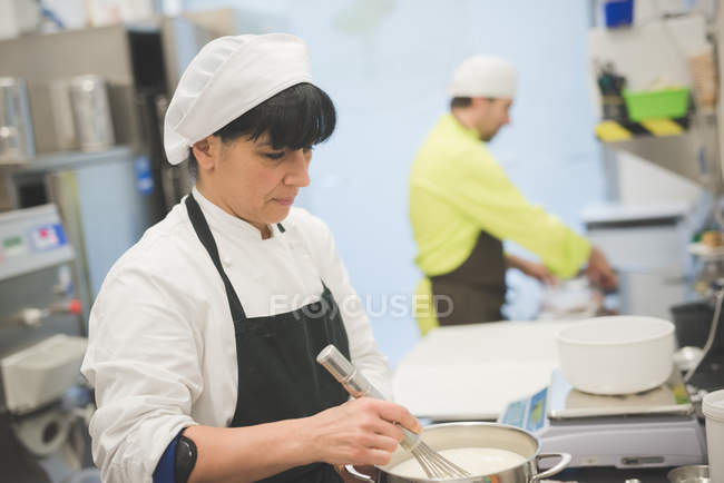 Panettieri maschi e femmine che lavorano in cucina commerciale — Foto stock
