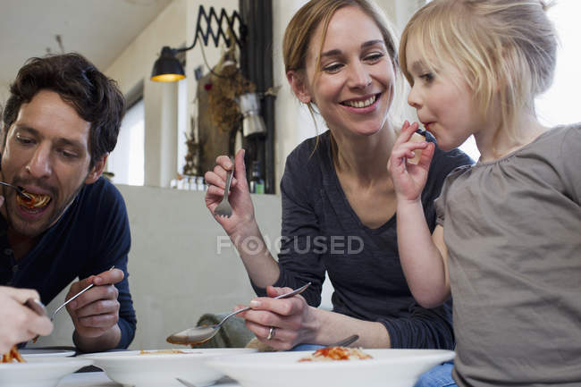 Metà genitori adulti e due figlie mangiare spaghetti pasto — Foto stock