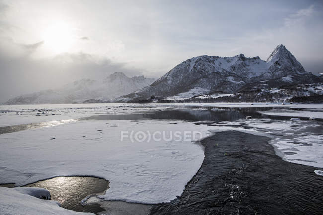 View of frozen shore and mountain with low clouds — Stock Photo