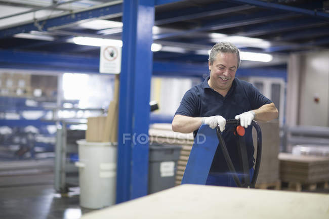 Trabalhador sênior da fábrica usando paletes de mão — Fotografia de Stock