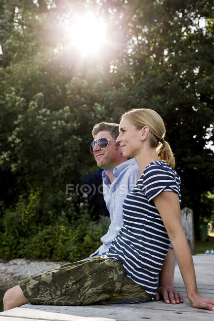 Пара сидить на дерев'яному причалі на березі озера — стокове фото