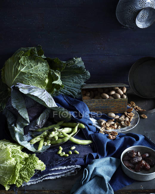 Натюрморт з сезонною капустою, зеленими бобами, фініками та пеканами — стокове фото