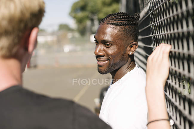 Two young men chatting by wire fence — Stock Photo