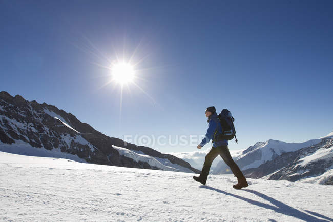 Senderismo de hombre a través del paisaje de montaña cubierto de nieve, Jungfrauchjoch, Grindelwald, Suiza - foto de stock