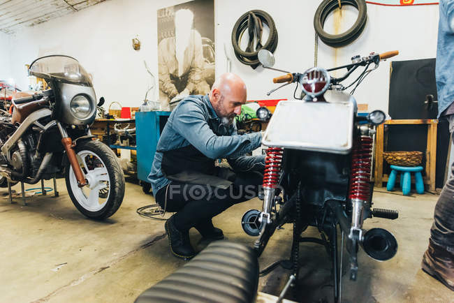 Maduro homem, trabalhando em motocicleta na garagem — Fotografia de Stock