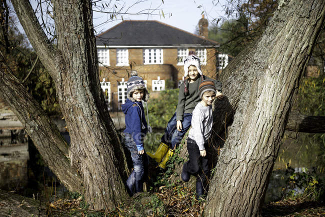 Retrato de tres jóvenes, apoyados en un árbol - foto de stock