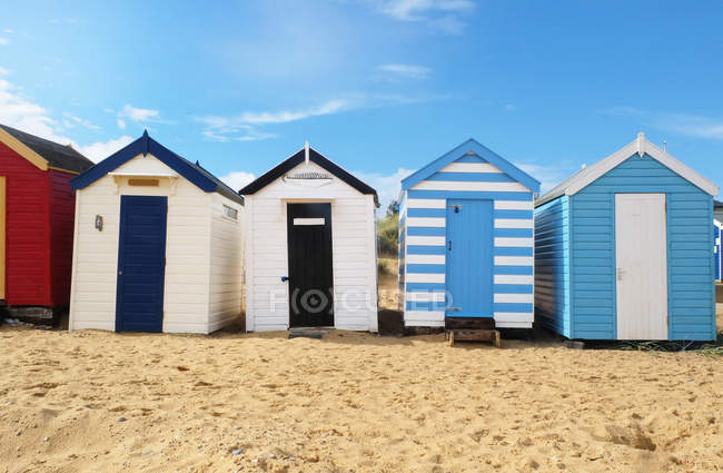 Fila de cabañas de playa en la arena en la luz del sol brillante - foto de stock