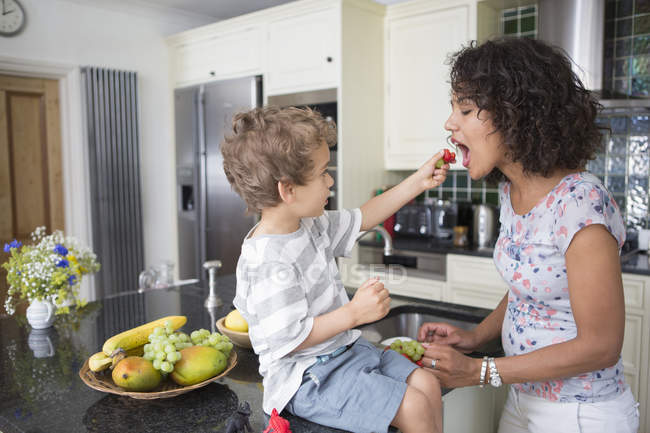 Mãe e filho na cozinha, compartilhando frutas — Fotografia de Stock