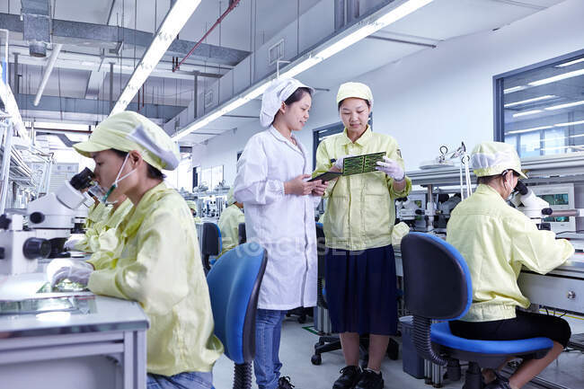 Supervisor, der die Arbeit an der Qualitätskontrollstation in der Fabrik überwacht, die flexible elektronische Leiterplatten herstellt. Werk befindet sich im Süden Chinas, in Zhuhai, Provinz Guangdong — Stockfoto
