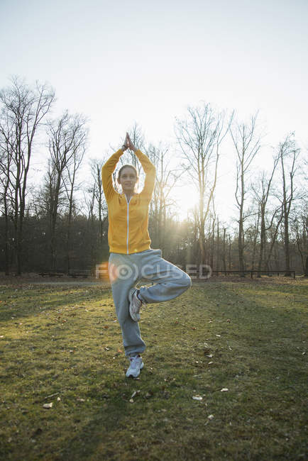 Young woman practicing yoga in field — Stock Photo