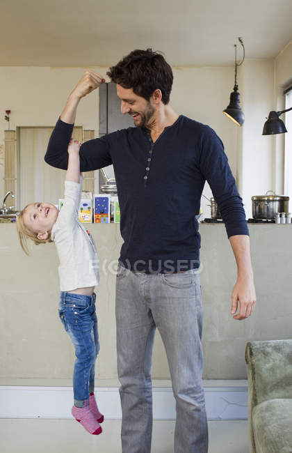 Little girl dangling from father arm — Stock Photo