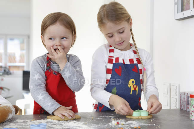 Chicas en el mostrador de cocina haciendo galletas sonriendo - foto de stock