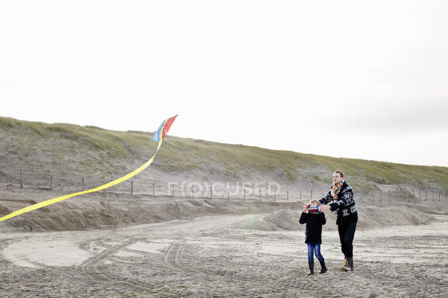 Hombre adulto y su hijo volando cometa en la playa, Bloemendaal aan Zee, Países Bajos - foto de stock