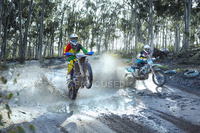 Dois pilotos de motocross do sexo masculino competindo em pista empoeirada — Fotografia de Stock