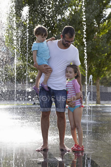 Pai e duas filhas brincando em fontes de água, Madri, Espanha — Fotografia de Stock