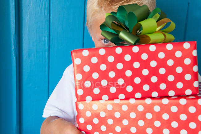 Boy peeping behind gifts in hand — Stock Photo