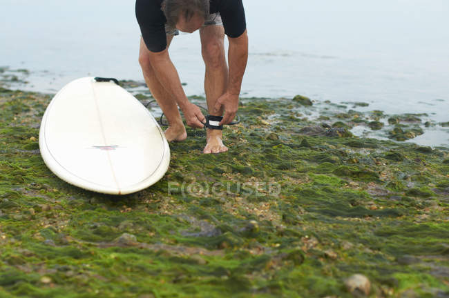 Surfer tying surfboard leash to ankle — Stock Photo