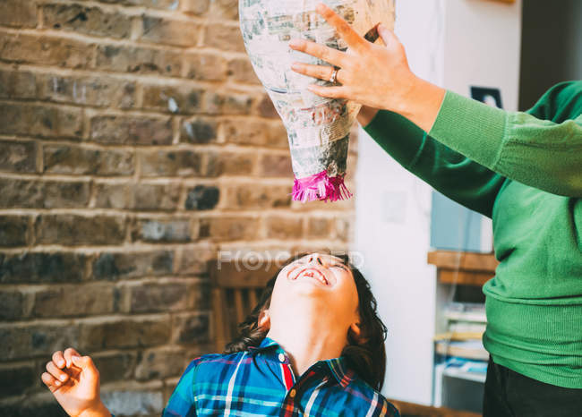 Mother and son playing with pinata at home — Stock Photo